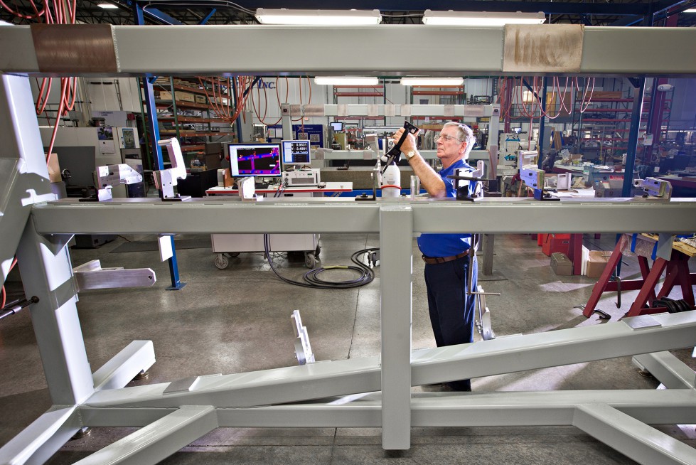 A Patriot Machine associate standing behind scaffolding for large bulkheads.