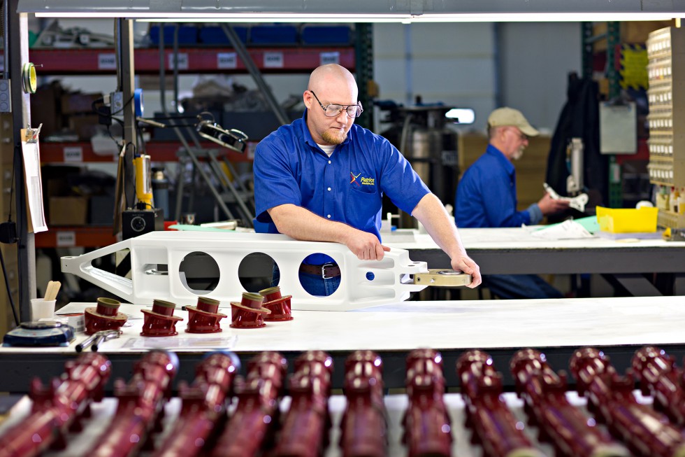 A Patriot Machine associate examining a hinge on a machined part for defects.