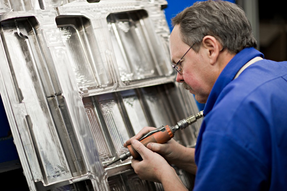 A Patriot Machine associate applying fine detail to a machined part using a sanding tool.