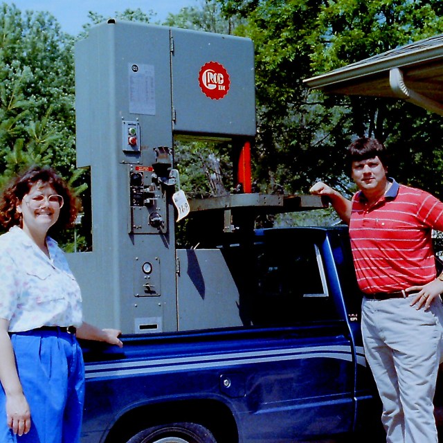 Young Bob and Judy Burns standing in front of a truck, their first machine in the bed.